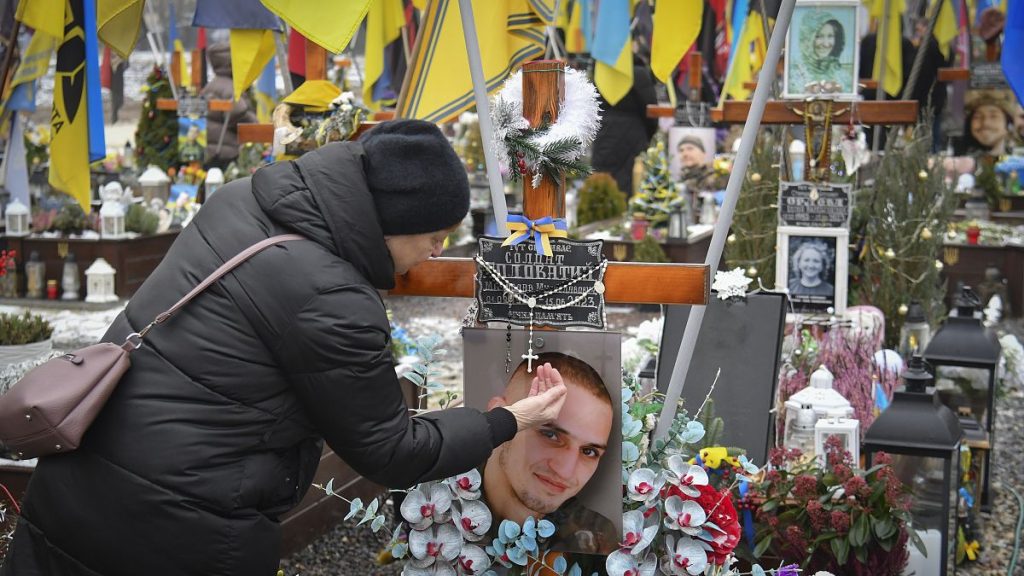 A relative prays at the tomb of a soldier killed defending Ukraine from the Russian invasion in Lviv, 28 December, 2024