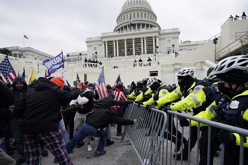 Des émeutiers franchissent une barricade de police devant le Capitole à Washington, le 6 janvier 2021.