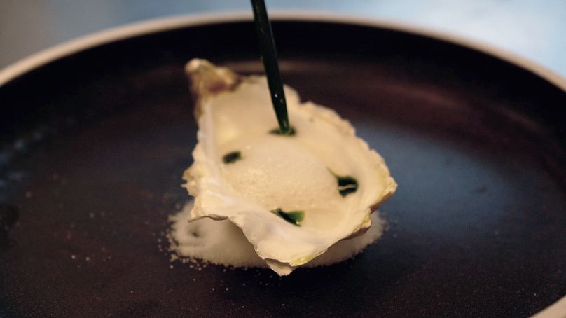 Un plat de preuve de concept à base de champignons servi dans une coquille d'huître avec de la mousse et de la sauce