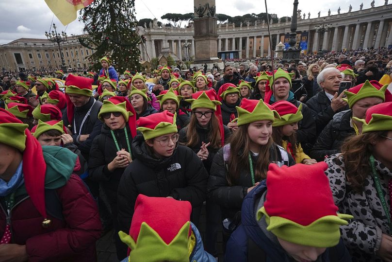 Des enfants prient pendant la prière de l'Angélus de midi dirigée par le pape François à l'occasion du jour de l'Épiphanie, depuis la fenêtre de son studio donnant sur la place Saint-Pierre, le 6 janvier 2025.