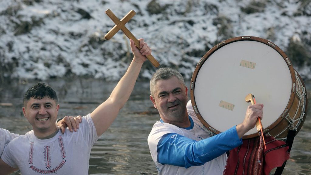 Bulgariana sing and dance and hold a wooden cross in the Lesnovska River during Epiphany Day celebrations in the town of Elin Pelin, Bulgaria, Monday, Jan. 6, 2025.