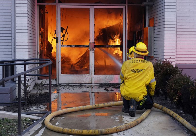 Les pompiers pointent un tuyau vers l'entrée d'une Bank of America en proie aux flammes sur Lake Avenue, le mercredi 8 janvier 2025.