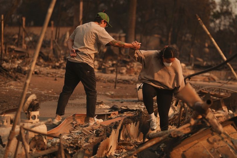 Deux personnes se tiennent la main alors qu'elles fouillent une propriété ravagée par un incendie à la suite de l'incendie d'Eaton le jeudi 9 janvier 2025.