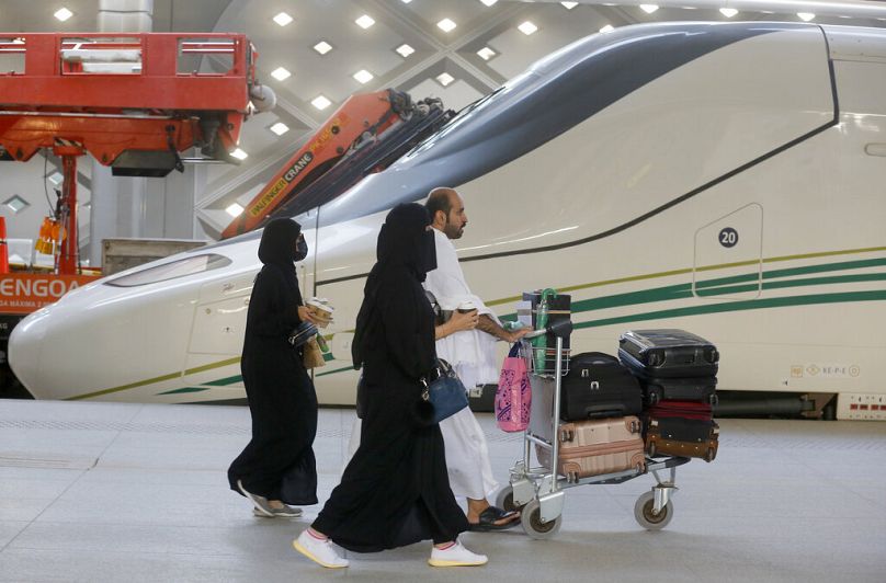 Des pèlerins en route vers la Mecque passent devant le train à grande vitesse Haramain dans la ville sainte de Médine, en Arabie Saoudite, le jeudi 8 août 2019. Des centaines de milliers de musulmans