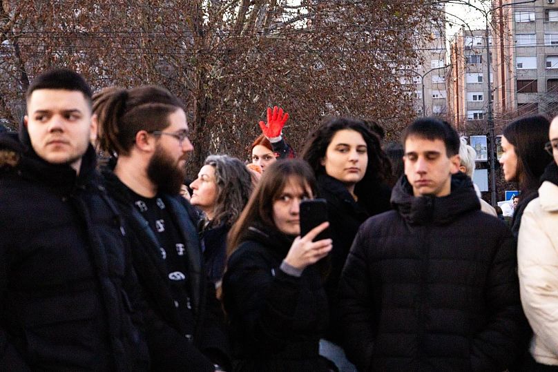 Un manifestant tient une main peinte en rouge en l’air.