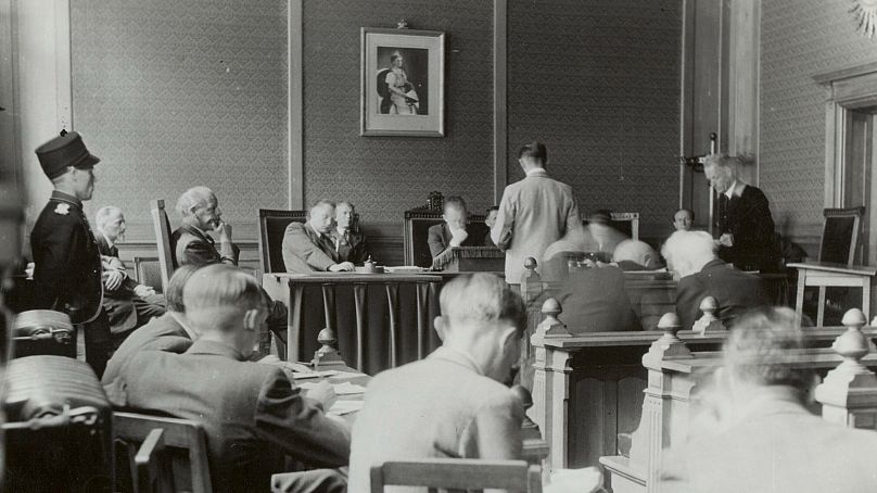 An accused Nazi collaborator stands before the president of the Special Jurisdiction Tribunal in Den Bosch, the Netherlands, in July 1945. 