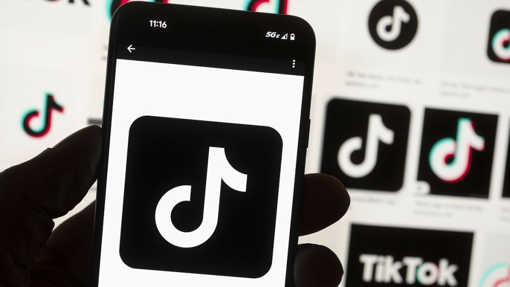 The TikTok logo is displayed on a mobile phone in front of a computer screen in Boston, 14 October, 2022