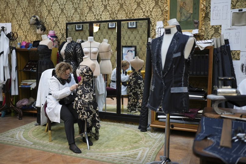 Une couturière travaille sur une robe pendant l'exposition 