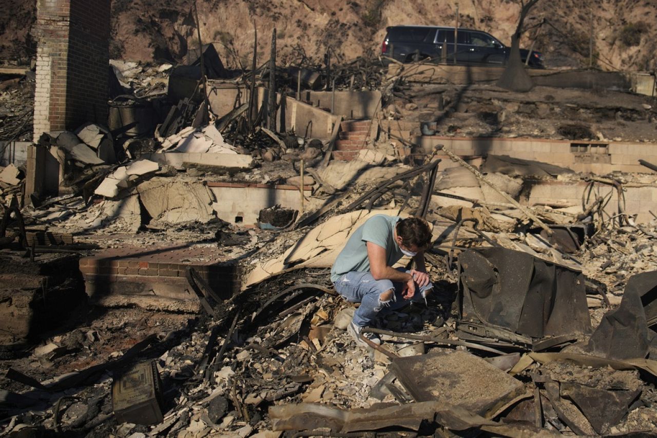 Luke Dexter s'agenouille alors qu'il passe au crible les restes de la propriété de son père en bord de mer ravagée par le feu à la suite de l'incendie des Palisades vendredi.