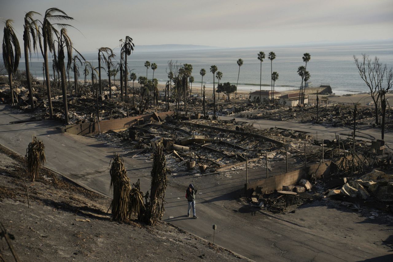 Une personne passe devant les dégâts causés par l'incendie de Palisades le vendredi 10 janvier 2025, dans la section Pacific Palisades de Los Angeles