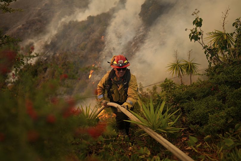 Un pompier installe un tuyau d'arrosage alors qu'il combat l'incendie de Palisades à Los Angeles, le 11 janvier 2025.