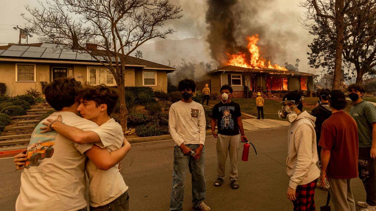 Residents embrace outside of a burning property as the Eaton Fire swept through Wednesday, Jan. 8, 2025 in Altadena, California