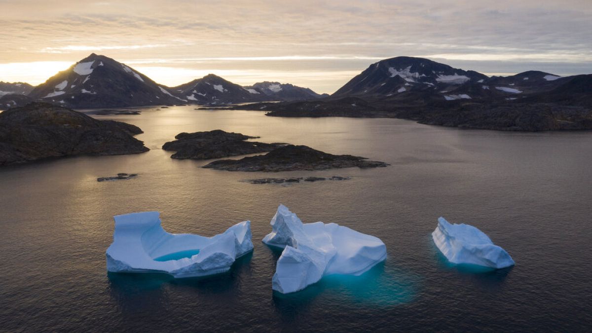 Large Icebergs float away as the sun rises near Kulusuk, Greenland.