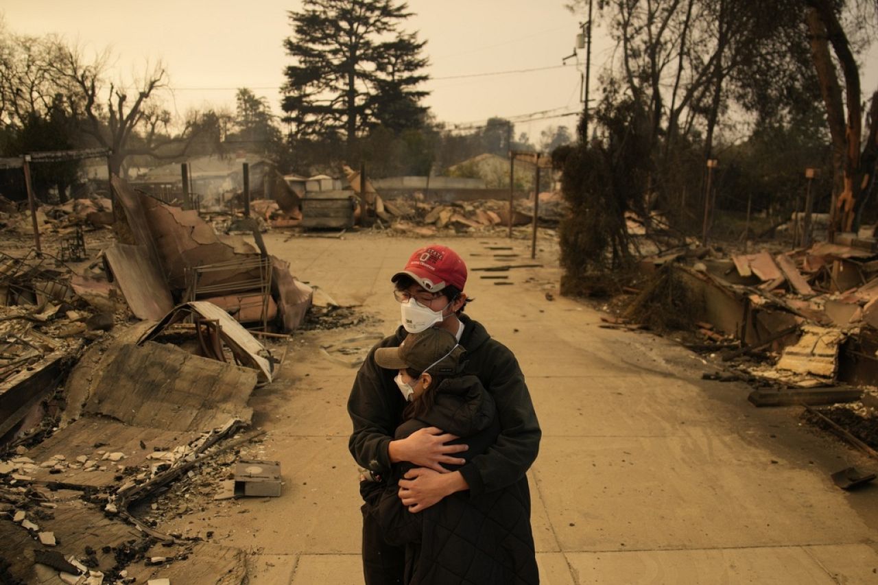 Ari Rivera, arrière, Anderson Hao se tiennent devant leur maison détruite à Altadena, en Californie, le 9 janvier 2025. 