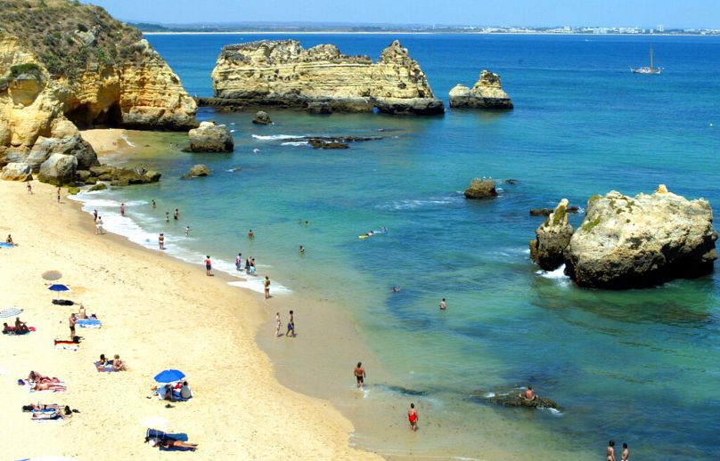 Les gens profitent du soleil et de l'eau rafraîchissante sur une plage juste à l'extérieur de Lagos, au Portugal, sur la côte de l'Algarve