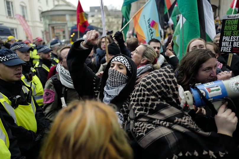 Des gens brandissent des drapeaux et des pancartes alors qu'ils sont confinés par des policiers lors d'un rassemblement de soutien au peuple palestinien à Londres, le 18 janvier 2025.