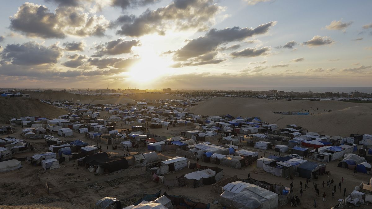 The sun sets above the Mawasi tent camp for displaced Palestinians in Khan Younis, 18 January, 2025