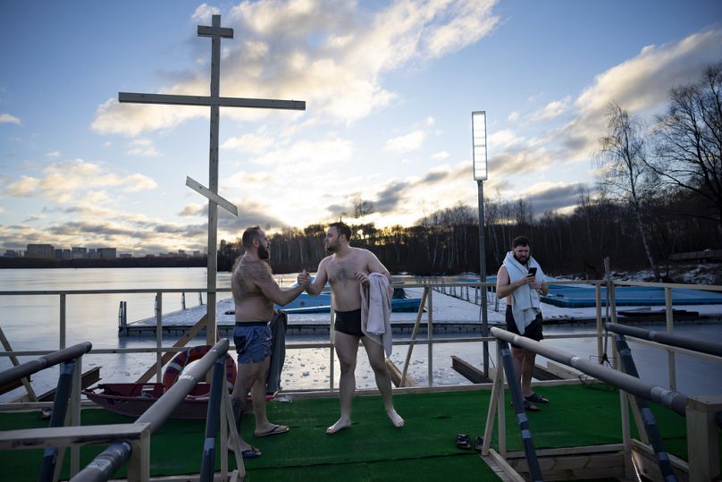 Deux hommes se félicitent après avoir plongé dans l'eau glacée avant de célébrer l'Épiphanie orthodoxe dans la plaine inondable de Stroginskaya à Moscou, en Russie, dimanche matin.