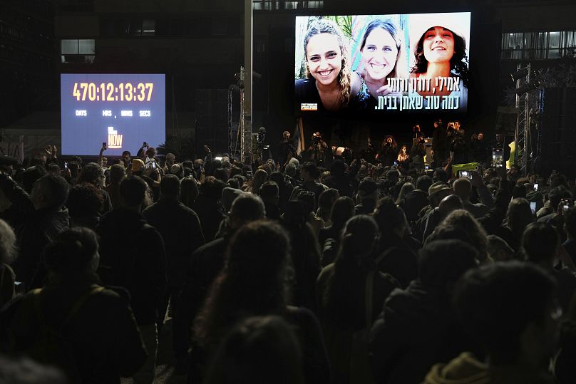 Les Israéliens réagissent alors que les photographies des femmes kidnappées en attente de libération, Romi Gonen, Doron Steinbrecher et Emily Damari, apparaissent sur l'écran à Tel Aviv, le 19 janvier 2025.