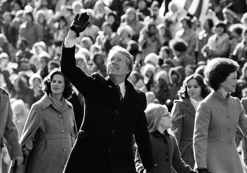 Jimmy Carter salue la foule alors qu'il marche avec sa femme Rosalynn le long de Pennsylvania Avenue et leur fille Amy