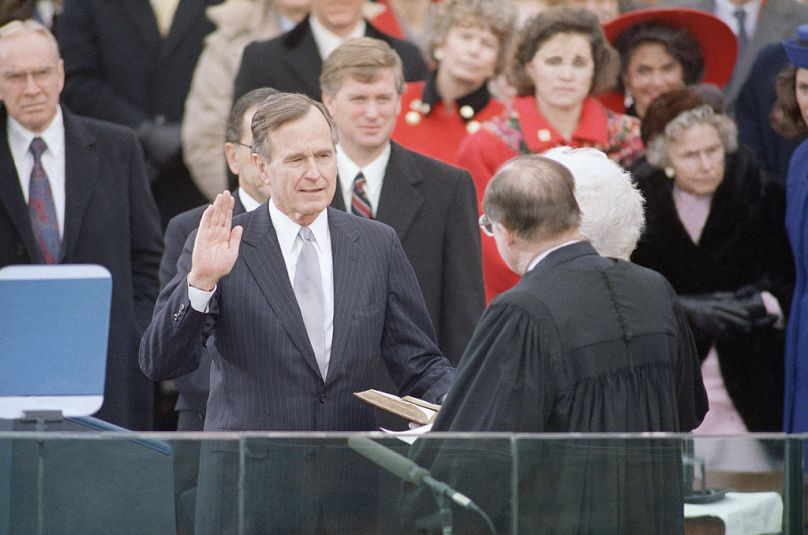   George Bush, à gauche, lève la main alors qu'il prête serment en tant que président des États-Unis devant le Capitole à Washington, le 20 janvier 1989.