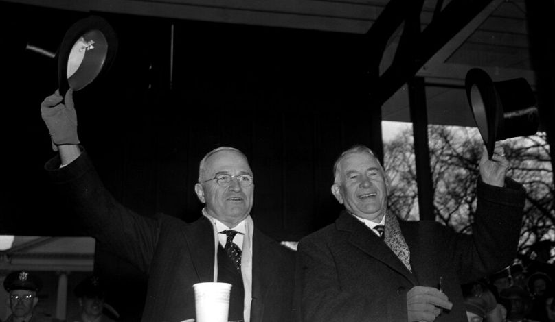   Harry S. Truman, à gauche, et le vice-président Alben W. Barkley saluent depuis le stand de revue du défilé inaugural devant la Maison Blanche après leur inauguration à Washington