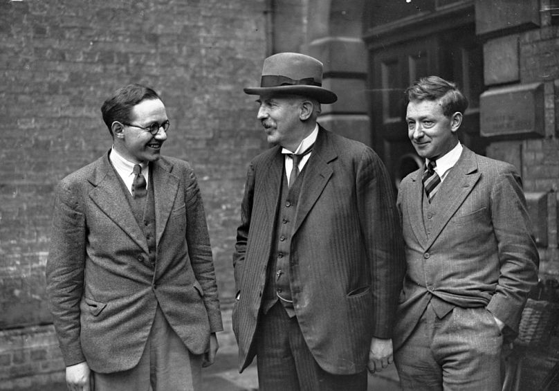 Le Dr ETS Walton, à gauche, et le Dr FD Cockroft, à droite, se tiennent aux côtés de Lord Rutherford devant le laboratoire Cavendish à Cambridge, au Royaume-Uni, le 2 mai 1932.