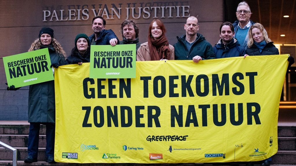 Greenpeace employees stand in front of the Palace of Justice in The Hague holding a banner reading ‘No Future Without Nature’ and green signs reading ‘Protect our nature’.