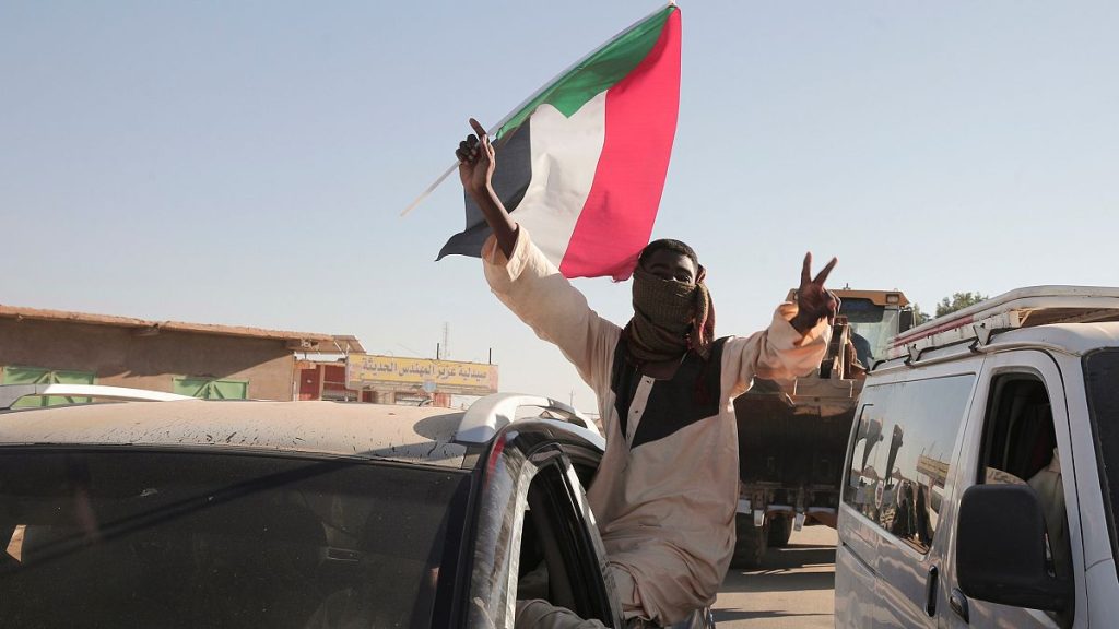 A Sudanese man gestures waving a Sudan flag following reports that Sudan