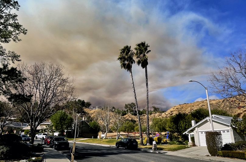 Un grand panache de fumée s'élève du lac Castaic, vu derrière un quartier de Santa Clarita, en Californie, le mercredi 22 janvier 2025.