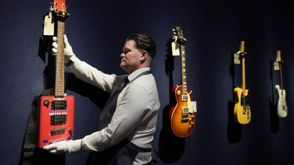 An art handler displays a Bohemian Guitars novelty electric guitar (Atlanta, Georgia, circa 2015) in London on Tuesday, 14 January 2025.