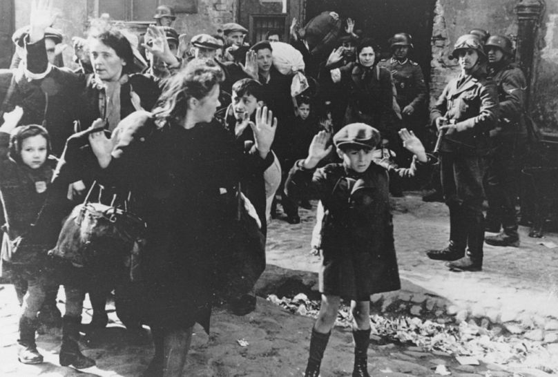   Un groupe de Juifs, dont un petit garçon, est escorté hors du ghetto de Varsovie par des soldats allemands le 19 avril 1943.