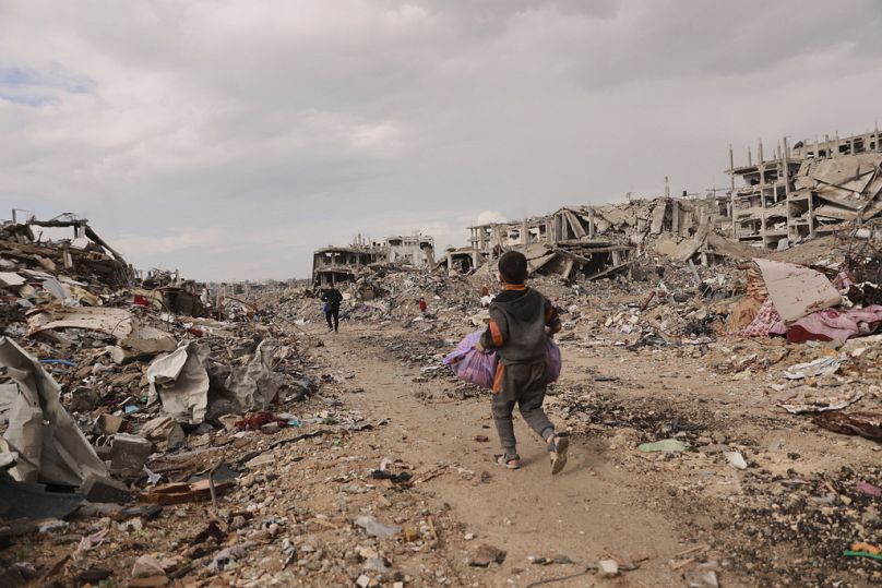 Un garçon palestinien porte ses effets personnels alors qu'il marche avec sa famille à côté des décombres des maisons détruites, après l'accord de cessez-le-feu entre Israël et le Hamas, à Gaza City