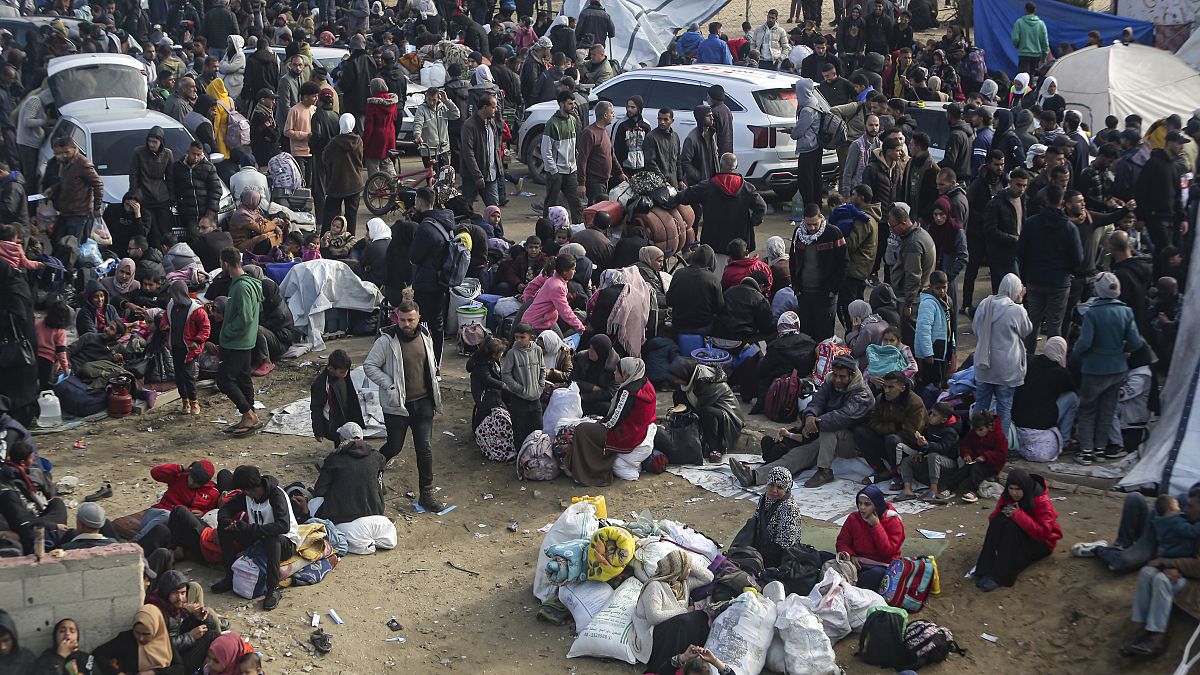 Displaced Palestinians gather with their belongings near a roadblock as they wait to return to their homes in the northern part of the Gaza Strip, 26 January, 2025