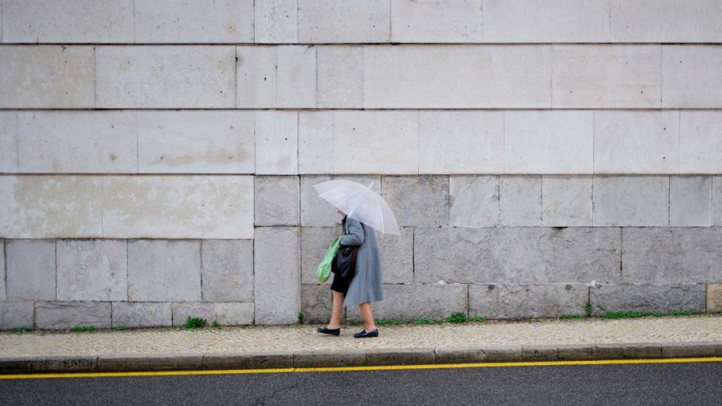 A woman walks with an umbrella in Lisbon.