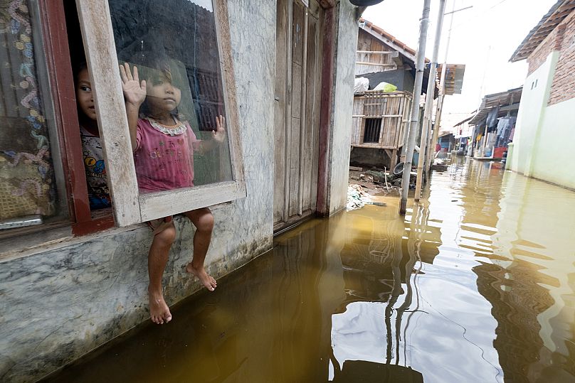 A little girl looks out over the flooded streets of her home in Indonesia.