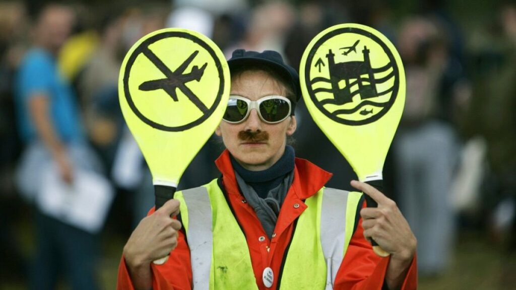 An environmental activist imitates an airport worker near London