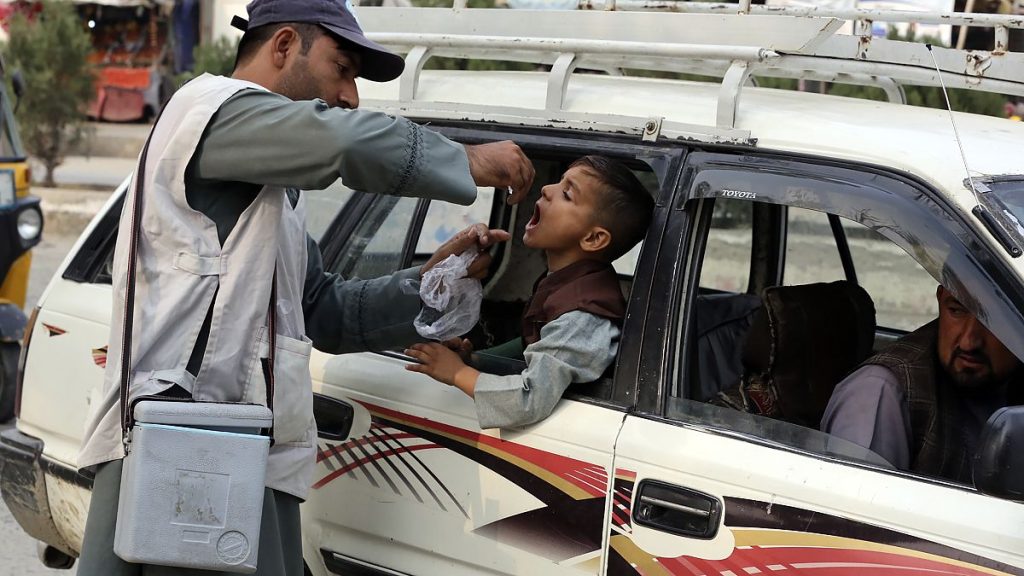 A health worker administers a polio vaccine to a child inside a taxi in the city of Jalalabad, Afghanistan, in October 2024.