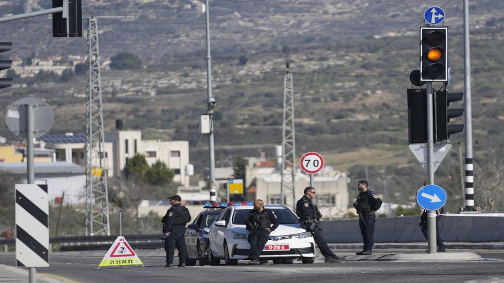 Israeli policemen block a main road after gunmen opened fire on cars and a bus carrying Israelis in the occupied West Bank, killing at least three people.