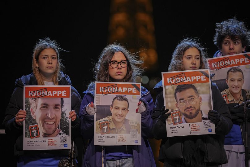 Des personnes tiennent des portraits d'otages sur scène lors d'un rassemblement à Paris, le 18 janvier 2025.