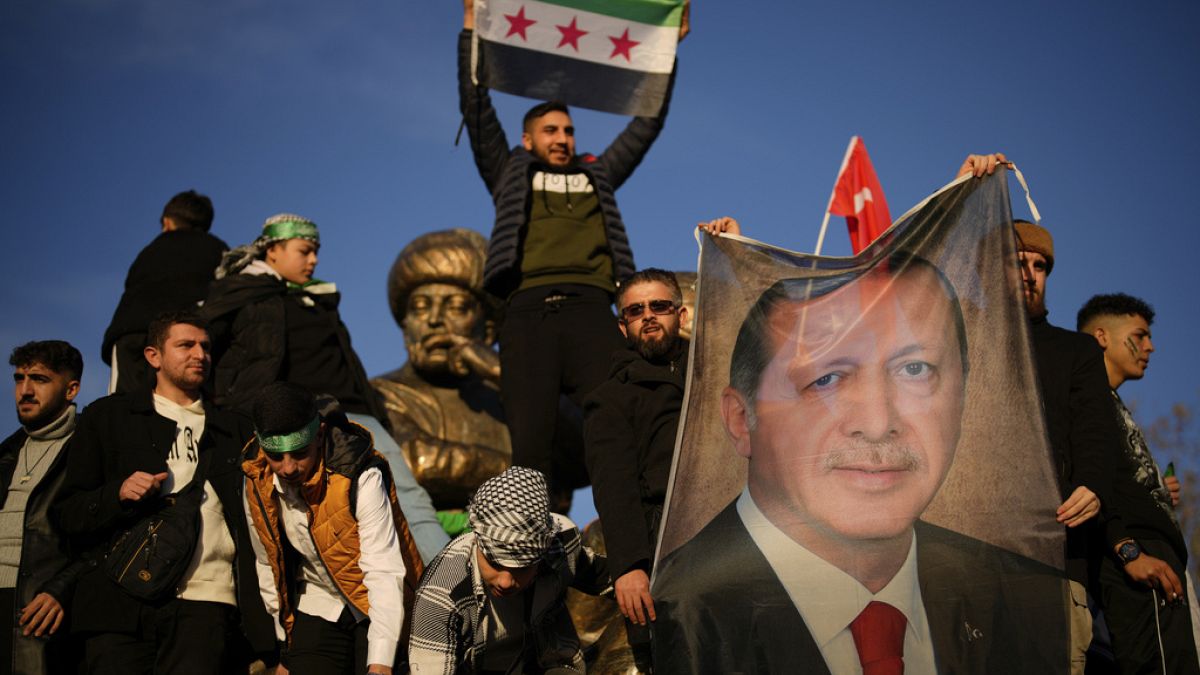 People hold a banner of Turkish President Recep Tayyip Erdogan as they celebrate the fall of the Syrian government in Istanbul, Turkey, on Sunday, Dec. 8, 2024