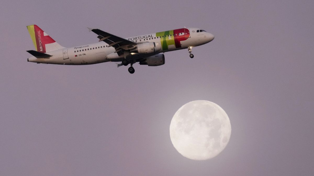 A TAP Air Portugal Airbus A320 approaches for landing in Lisbon, Portugal with the full moon in the background. 16 December 2024.