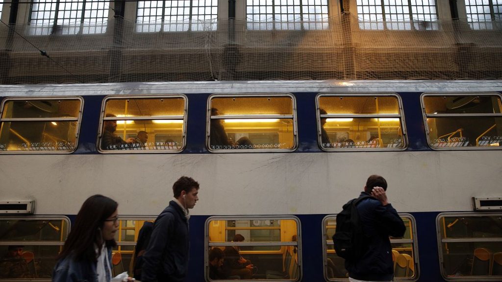 Commuters walk past a train at Gare de Lyon train station, in Paris.