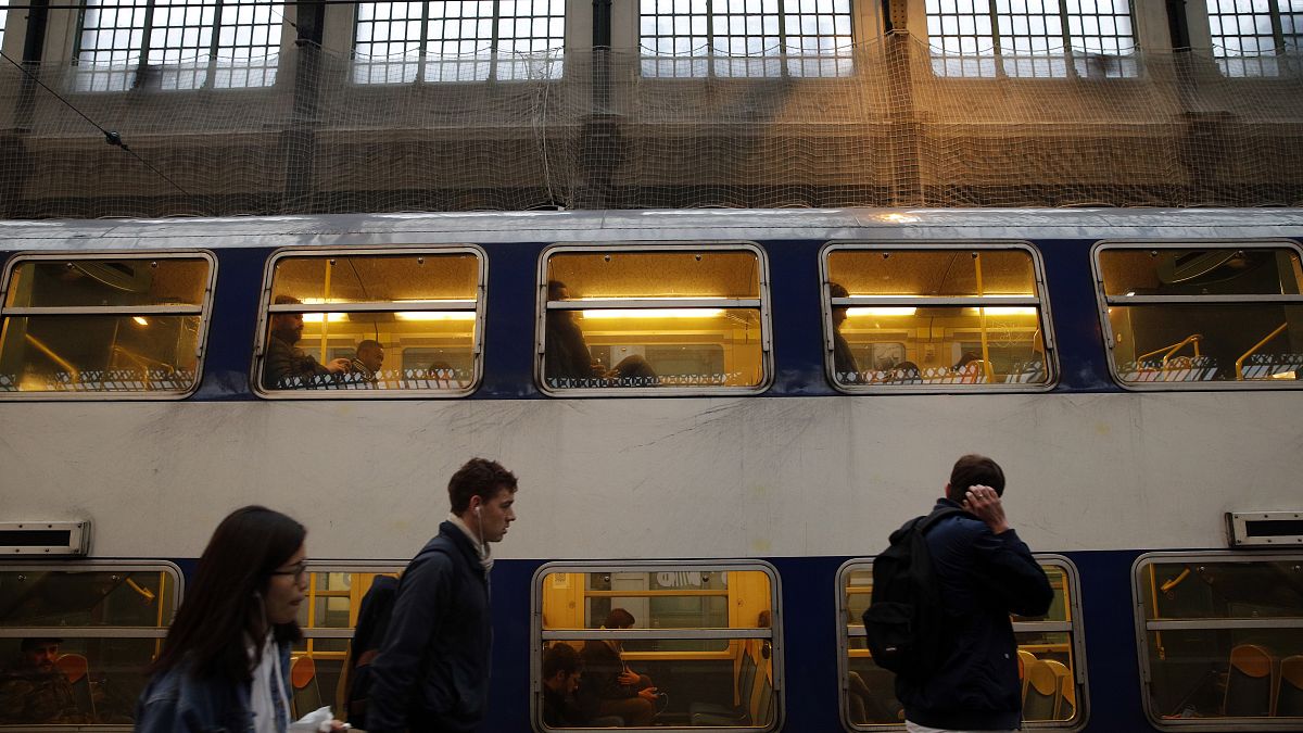 Commuters walk past a train at Gare de Lyon train station, in Paris.