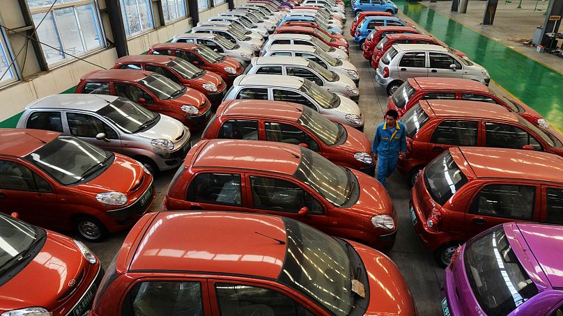 Un ouvrier marche parmi des voitures électriques dans une usine du comté de Zouping, dans la province du Shandong (est de la Chine), 2013.