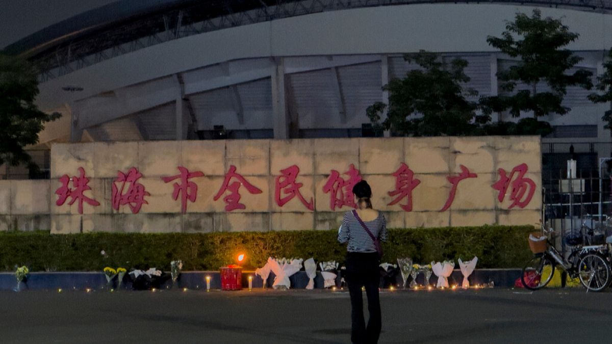 FILE - A woman stands near flowers placed outside the "Zhuhai People