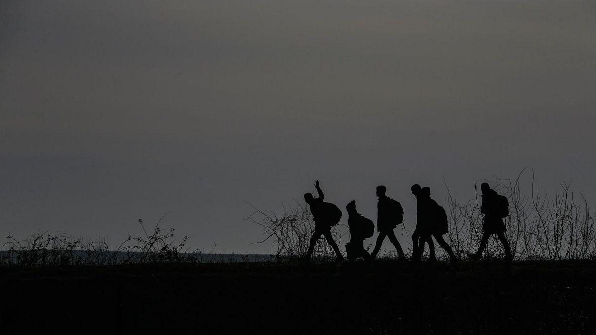 FILE - Migrants walk to enter Greece from Turkey by crossing the Maritsa river (Evros river in Greek) near the Pazarkule border gate in Edirne, Turkey, 1 March 2020.