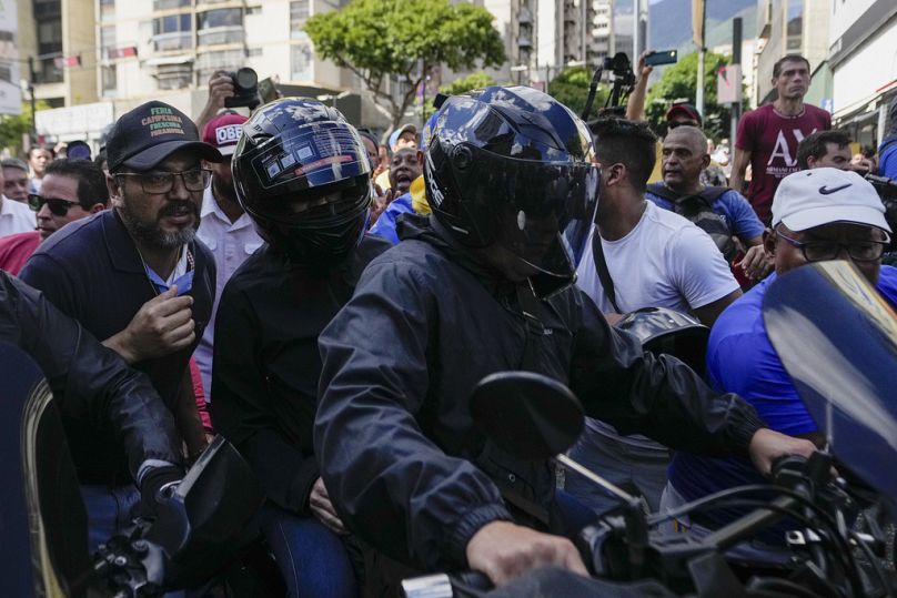 La chef de l'opposition Maria Corina Machado, portant un casque, est assise à l'arrière d'une moto alors qu'elle s'éloigne après s'être adressée aux gens lors d'une manifestation, le 9 janvier 2025.