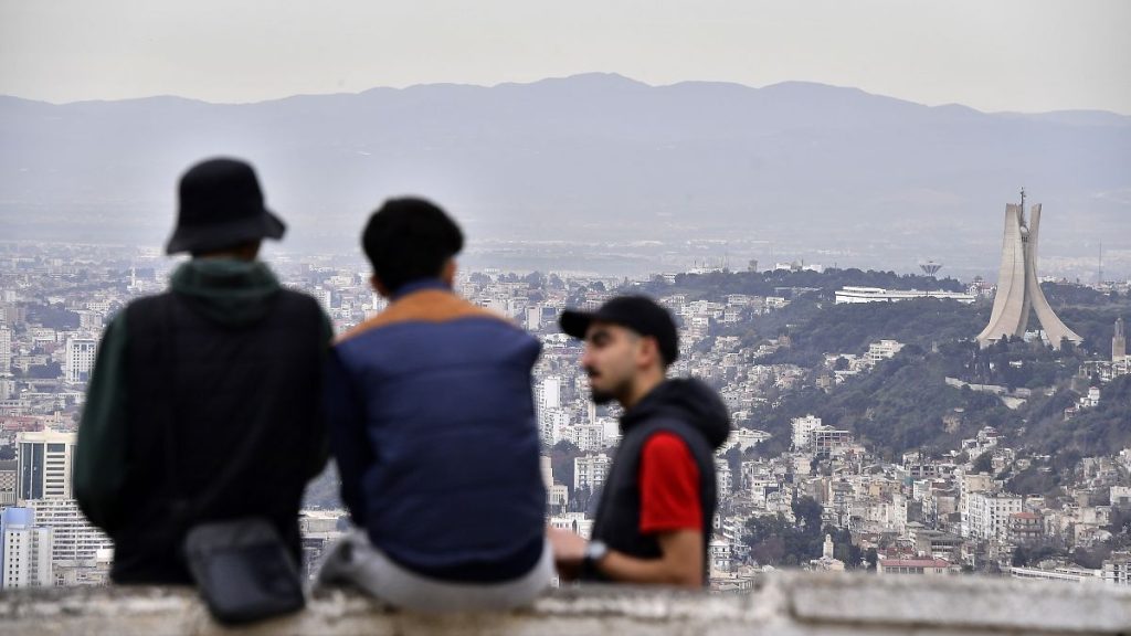 Residents talk, with the monument to the Martyrs in background, right, Monday, Jan. 6, 2025 in Algiers.