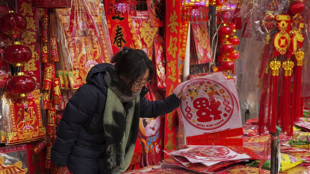 A woman shops for prosperity decorations at a shop in Beijing ahead of the Chinese Lunar New Year